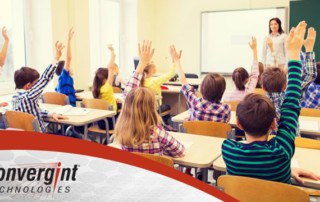 Children in classroom raising hands