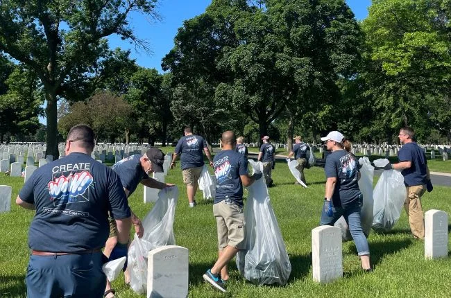 A group of people picking up trash in a cemetery 