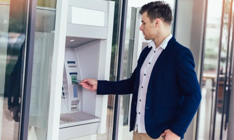 Man standing in front of an ATM entering his card